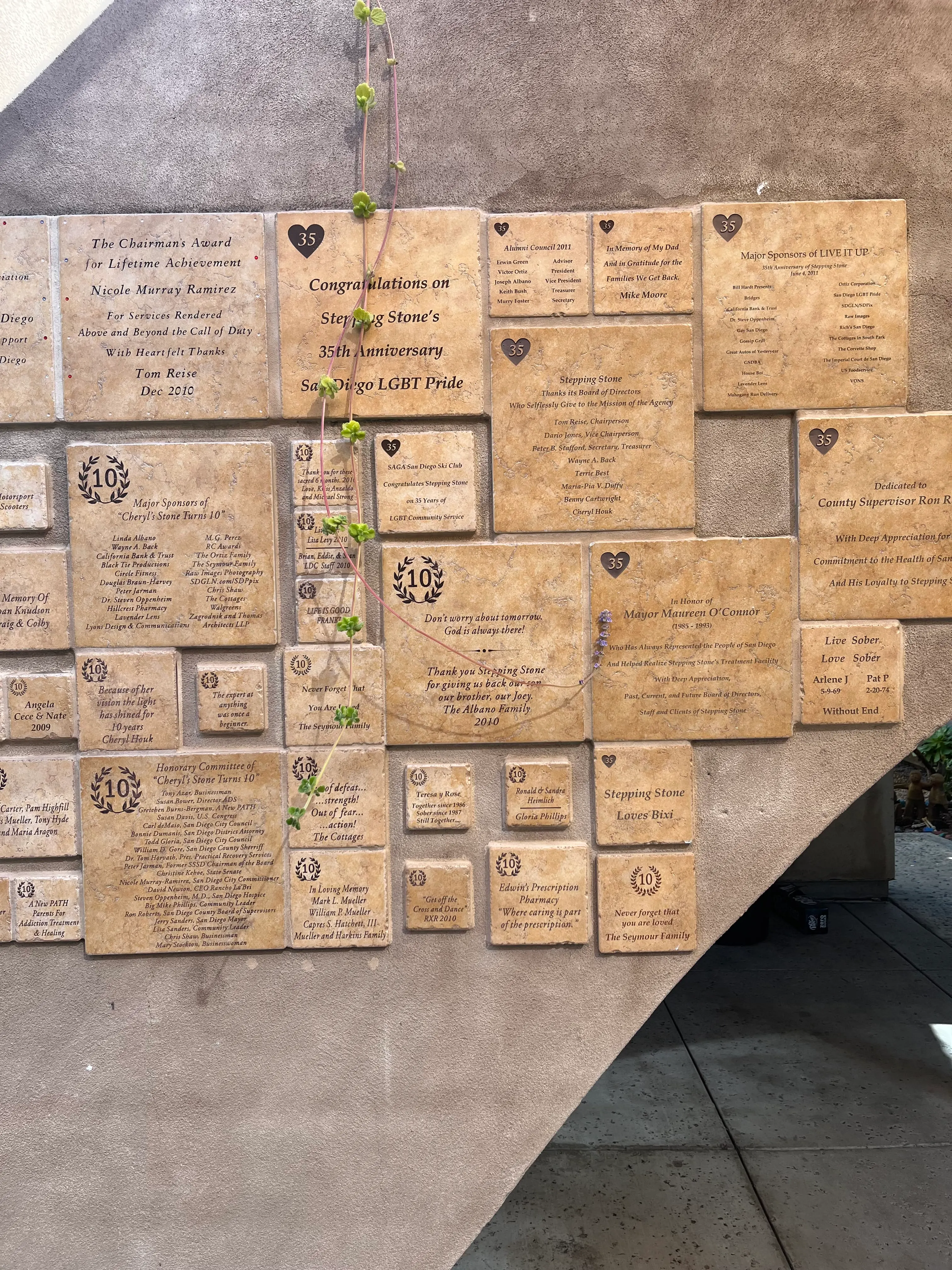 Engraved commemorative tiles mounted on the courtyard wall at Stepping Stone, including a 35th-anniversary dedication